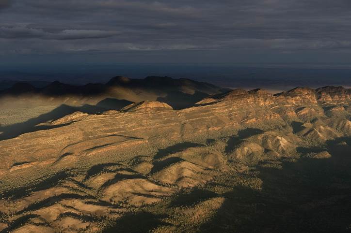 Sunlight casts light and shadow on a desert mountain range.