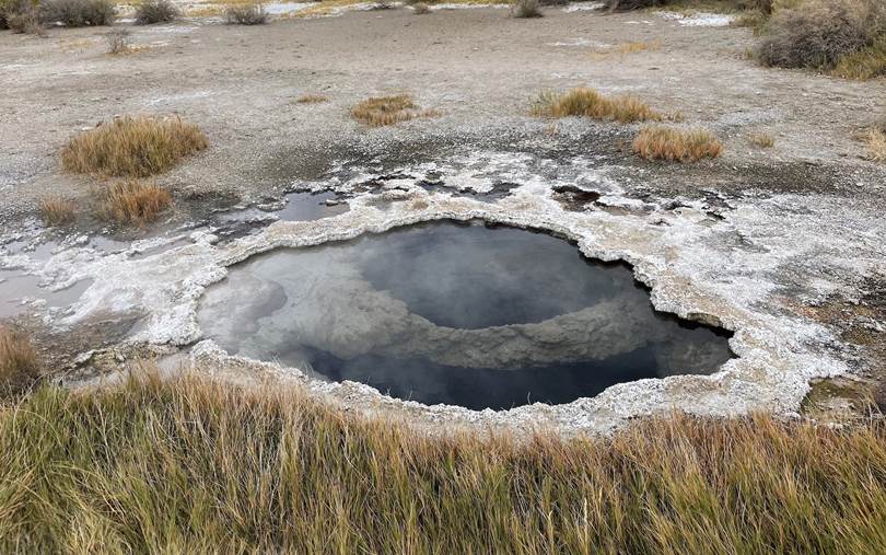 small dark pool surrounded by white salt and reeds