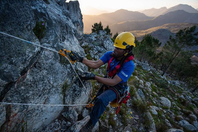 a person climbing a rock face in climbing gear.
