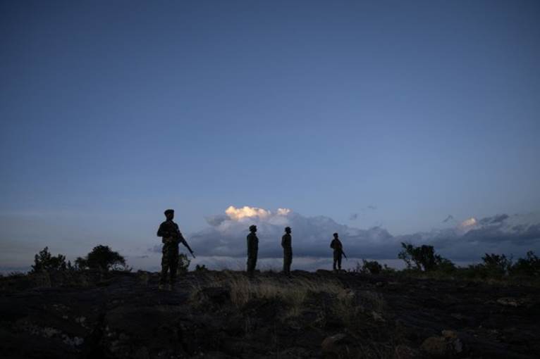 Four rangers standing with guns gazing off into the distance. The photo is taken at dawn and you can only see their silhouettes against a backdrop of clouds. 